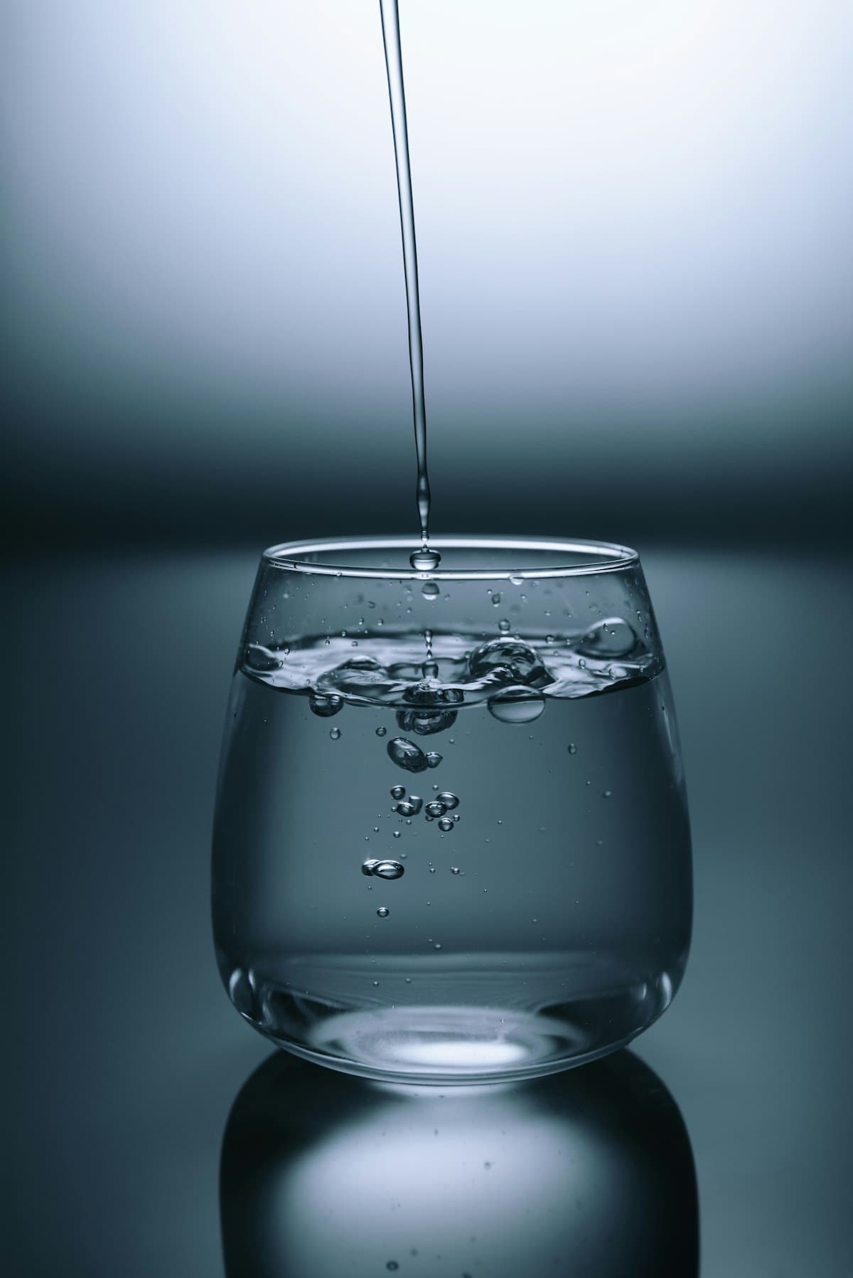 Vaso de agua purificada sirviéndose sobre fondo oscuro